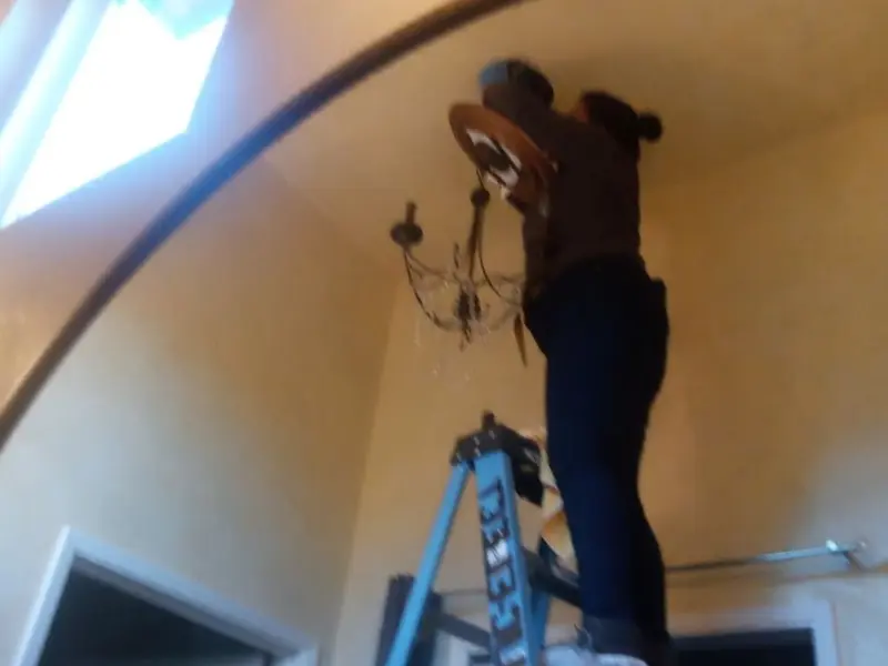 Electrician installing a chandelier in a Indialantic residence